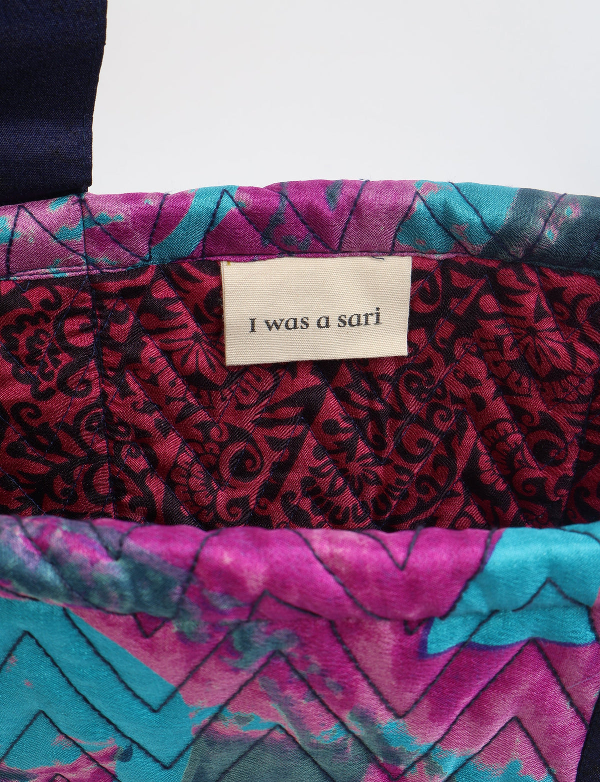 Quilted tote bag interior with pink, teal, and black abstract pattern and label reading "I was a sari"