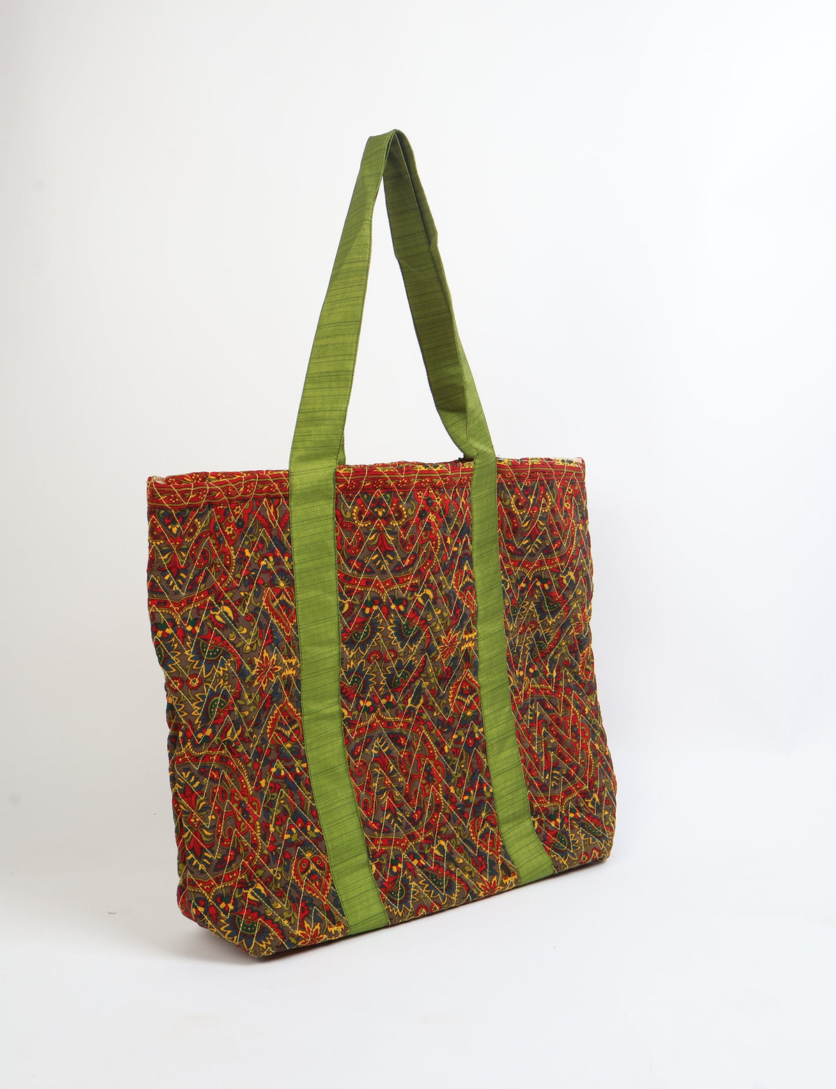 Quilted tote bag with red paisley pattern and green fabric handles, shown standing on white background