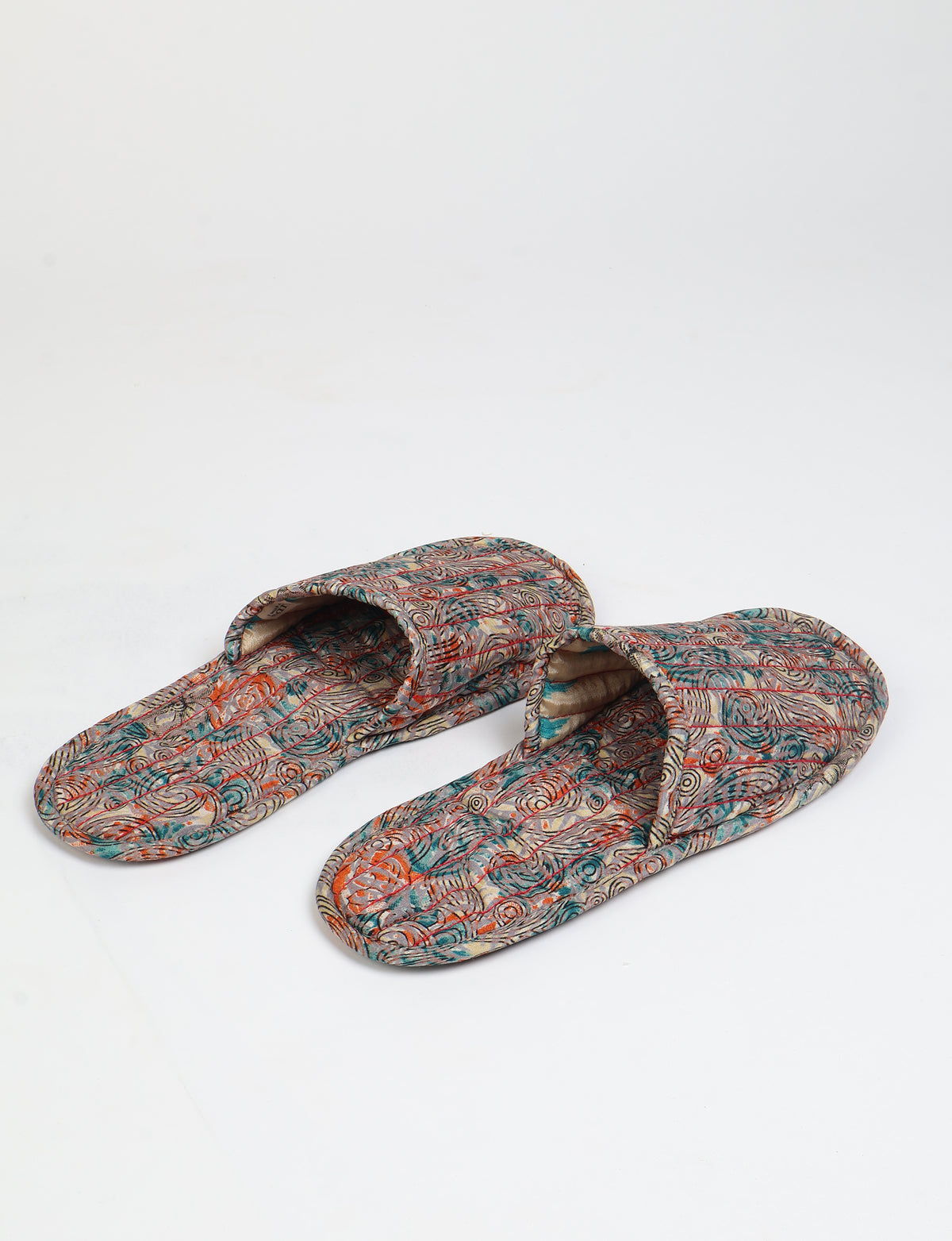 Beige quilted slippers with multicolor paisley pattern, open back, flat sole, shown from top angle on white background