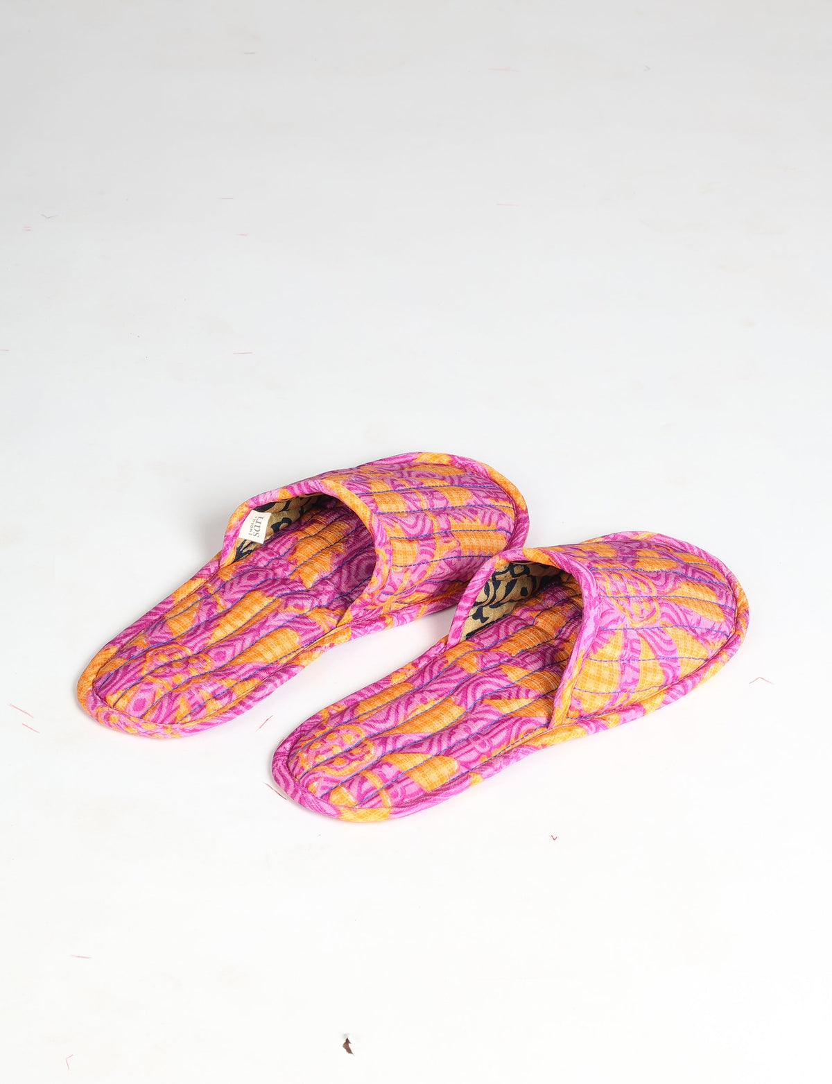 Quilted slippers in pink and orange floral pattern with open toe design, shown from top angle on white background