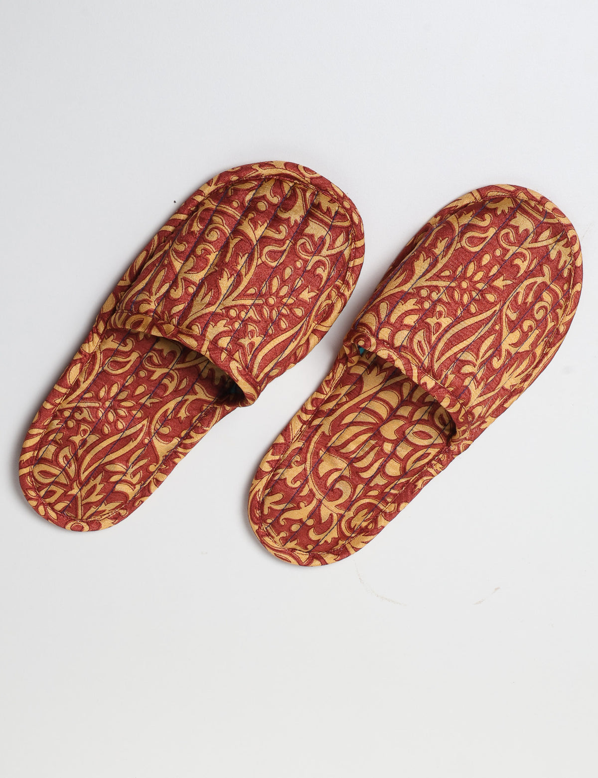 Blue quilted slippers with paisley pattern, open back, and cushioned footbed, shown flat on white background