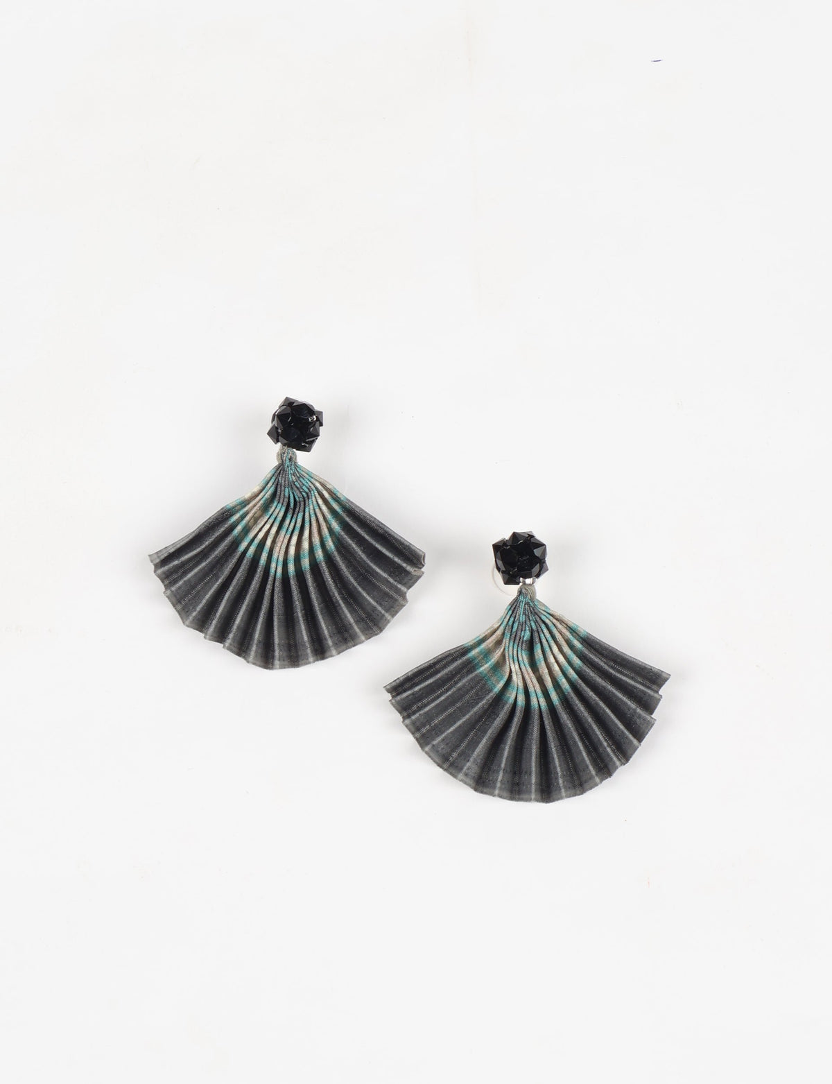 Grey pleated fabric earrings with abstract turquoise and beige pattern and black faceted stud tops, flat lay on white background