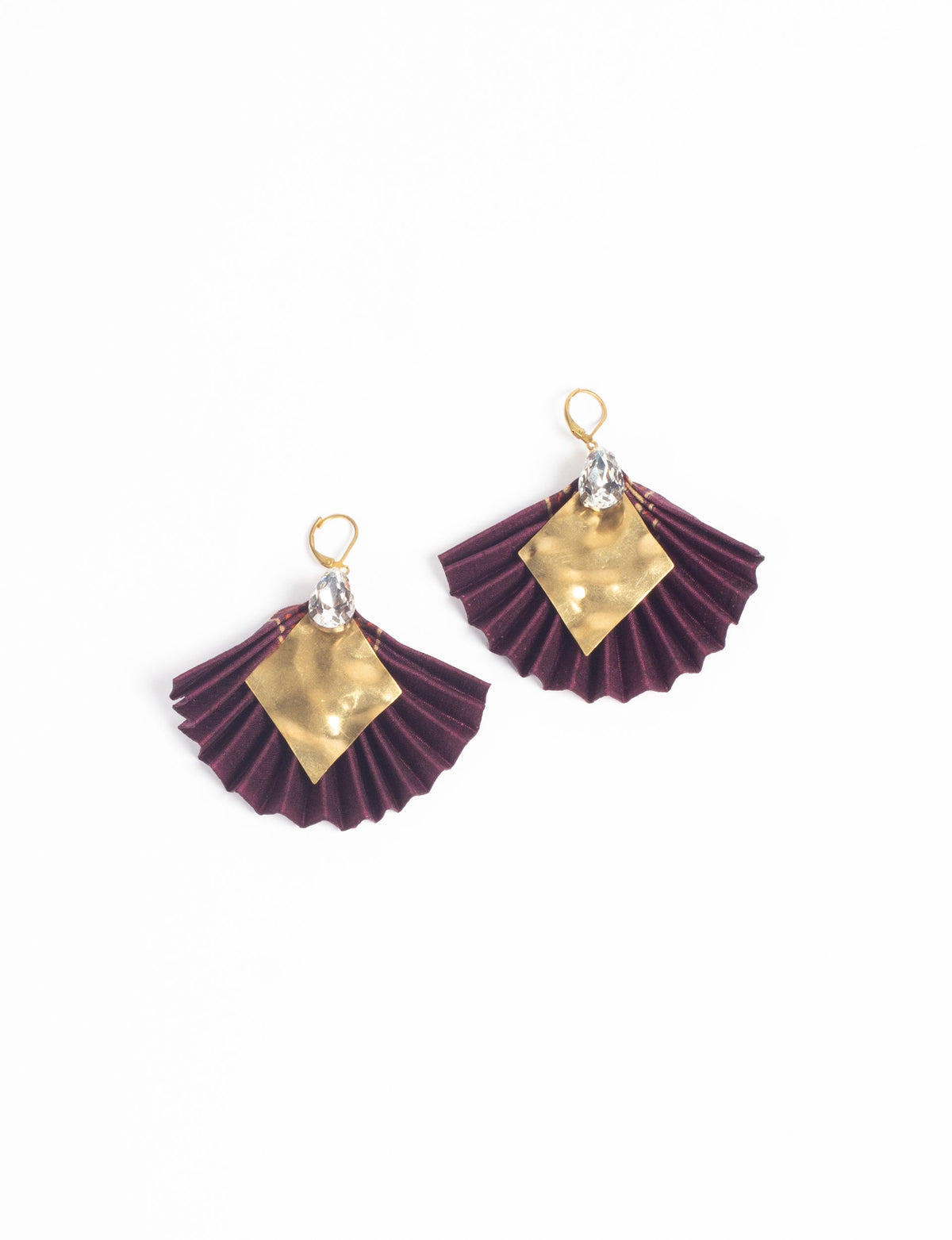 Pair of pleated purple fabric earrings with gold diamond-shaped metal accents and clear teardrop crystals, flat lay view