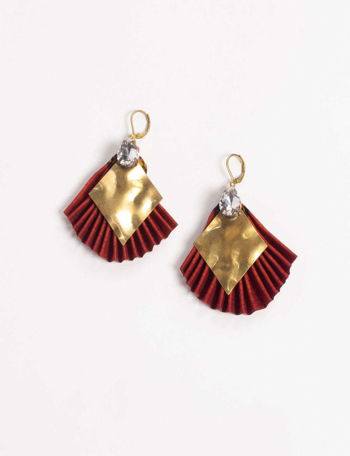 Red pleated fabric earrings with hammered gold diamond-shaped metal and clear teardrop crystals, shown flat on white background