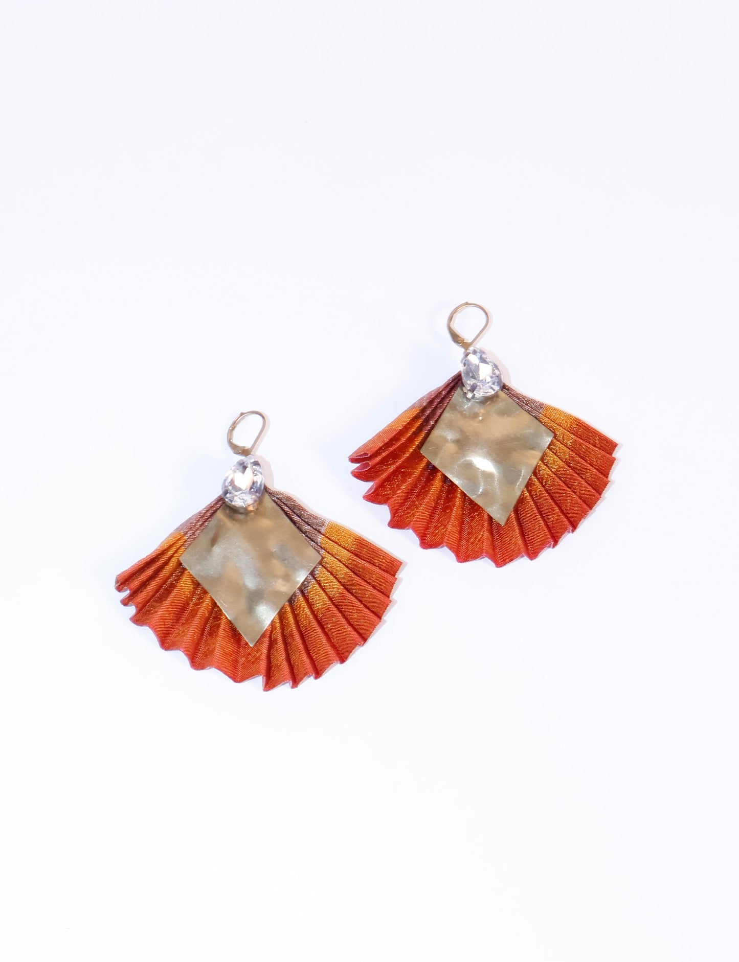 Elevate your style sustainably with our PLEATED EARRINGS – a fusion of ethical fashion and eco-conscious design. Created from pre-loved saris using heat set pleats, these earrings embody zero waste clothing and upcycled fashion. Fastened with hooks, adorned with a diamond-shaped metallic plate and a special drop-shaped jewel. Hypoallergy tested metal hooks, nickel, and lead-free, making them a conscious and skin-friendly accessory.