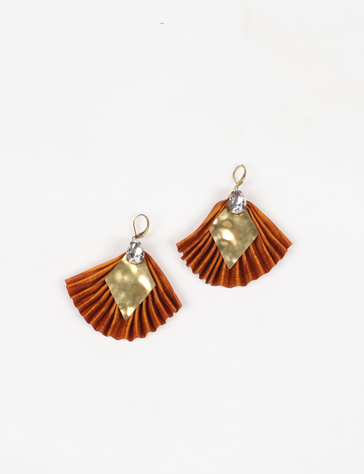 Orange pleated fabric earrings with gold diamond-shaped metal and clear teardrop crystals, shown flat on white background