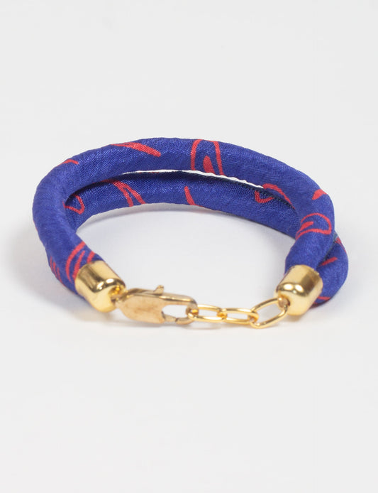 A close-up image of a hand wearing the Sari Rope bracelet, showcasing its colorful threads and unique design. This accessory embodies ethical fashion and sustainability, crafted from repurposed saris for a stylish and eco-conscious statement.