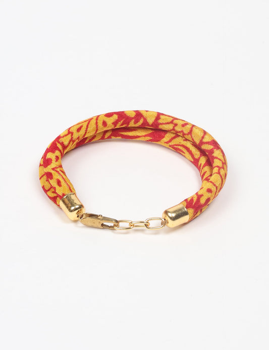 A close-up image of a hand wearing the Sari Rope bracelet, showcasing its colorful threads and unique design. This accessory embodies ethical fashion and sustainability, crafted from repurposed saris for a stylish and eco-conscious statement.