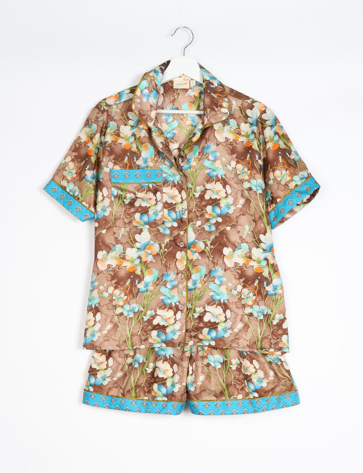Brown floral short-sleeve pajama set with blue trim on sleeves, pocket, and shorts hem, hanging on white hanger
