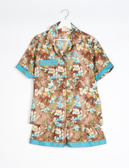 Brown floral short-sleeve pajama set with blue trim on sleeves, pocket, and shorts hem, hanging on white hanger