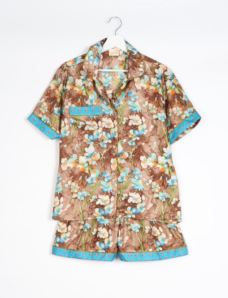 Brown floral short-sleeve pajama set with blue trim on sleeves, pocket, and shorts hem, hanging on white hanger