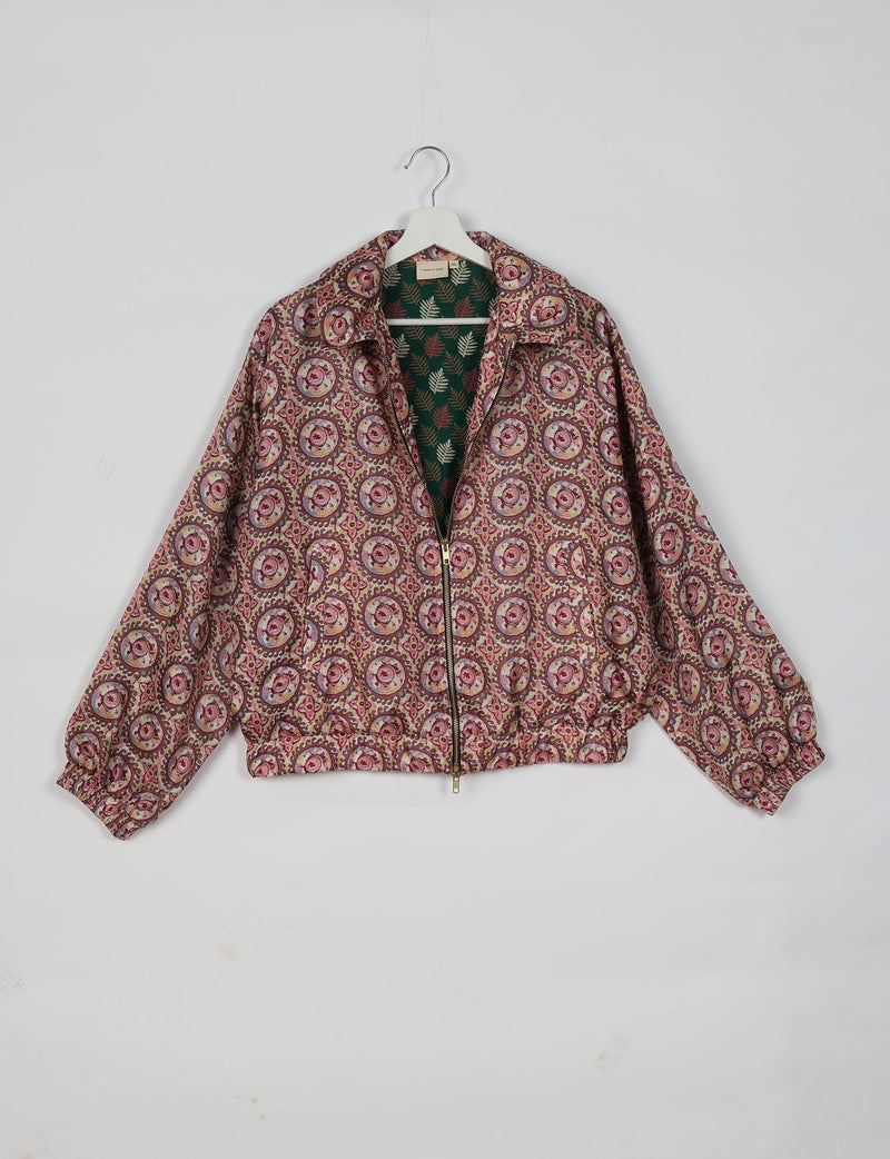 Bomber jacket in brown with circular floral pattern, zip front, elastic cuffs, and tropical leaf print lining, hanging on white hanger