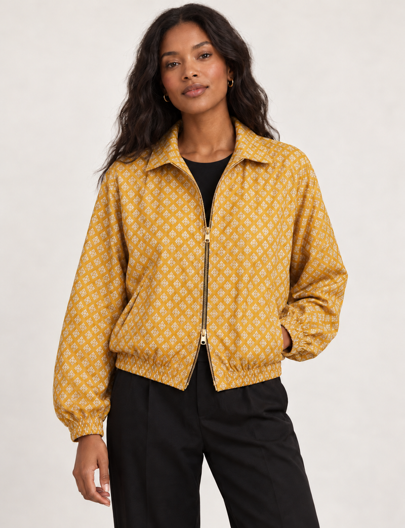 Woman wearing a yellow floral bomber jacket with front zipper, elastic cuffs, and side pockets, shown from front view