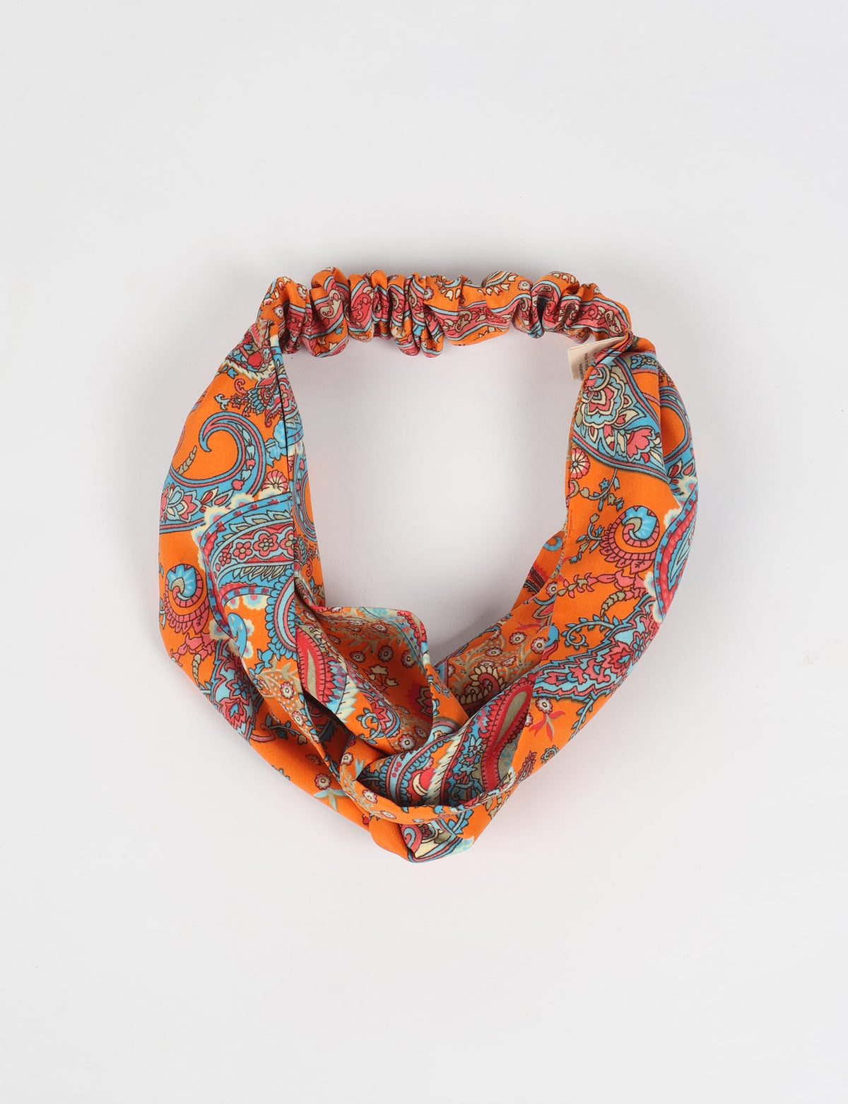 Orange tropical patterned fabric turban with paisley design and elastic back, shown flat on white background