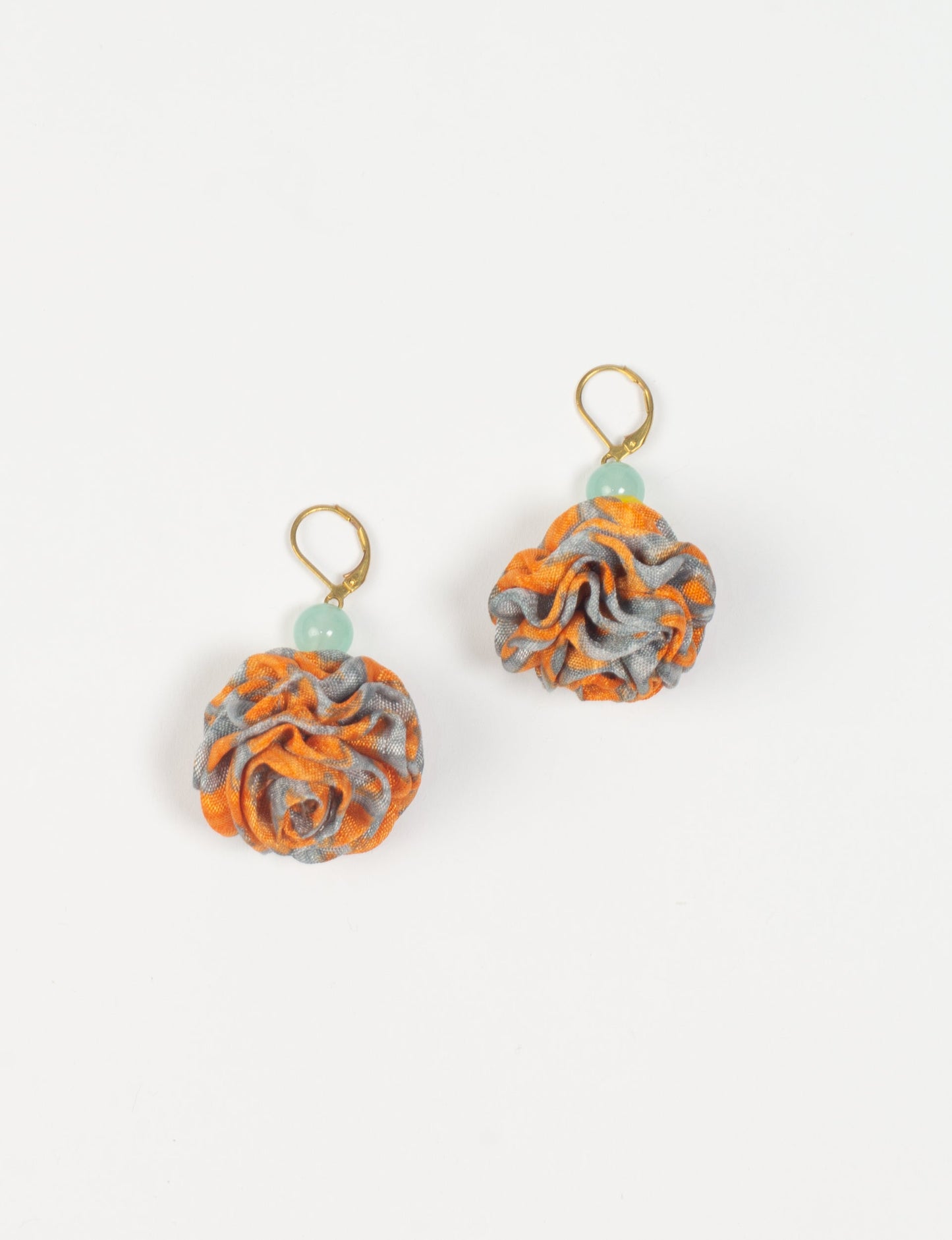 Elevate your style with our Ruffle Earrings, adorned with unique ruffle ball florets crafted from upcycled Indian saris using the traditional Aari embroidery technique. These sustainable earrings feature two glass beads and nickel-free, hypoallergenic metal hooks. Embrace ethical and green fashion with these statement pieces.