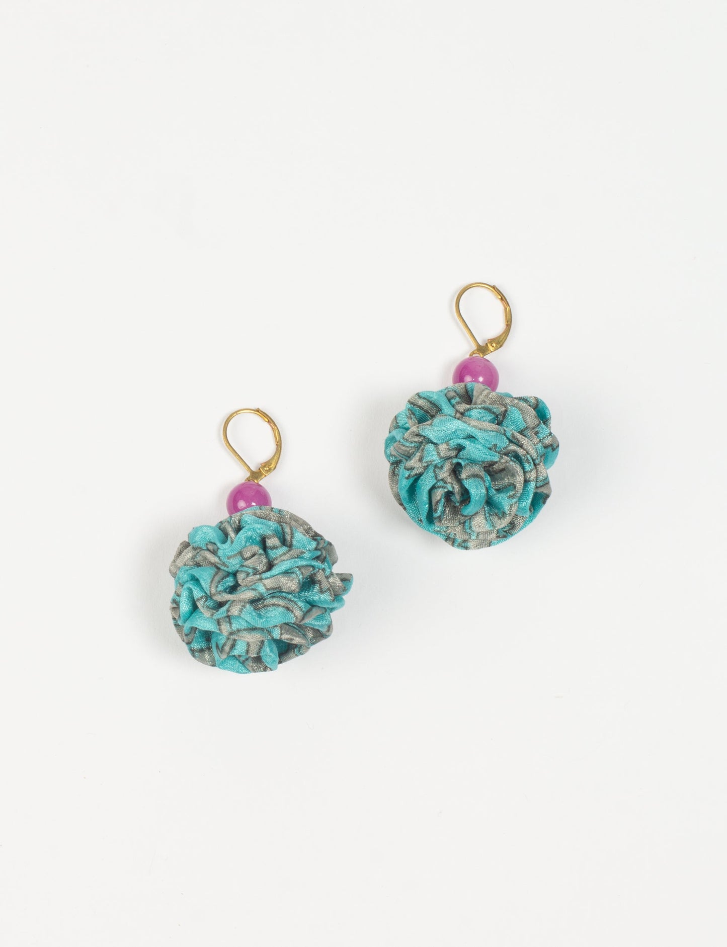 Elevate your style with our Ruffle Earrings, adorned with unique ruffle ball florets crafted from upcycled Indian saris using the traditional Aari embroidery technique. These sustainable earrings feature two glass beads and nickel-free, hypoallergenic metal hooks. Embrace ethical and green fashion with these statement pieces.