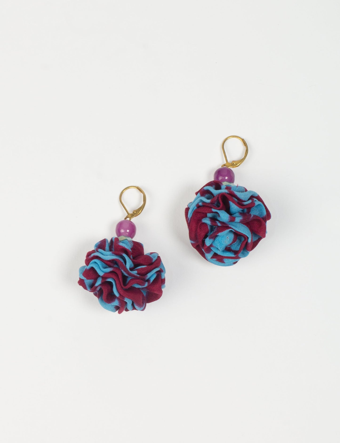 Elevate your style with our Ruffle Earrings, adorned with unique ruffle ball florets crafted from upcycled Indian saris using the traditional Aari embroidery technique. These sustainable earrings feature two glass beads and nickel-free, hypoallergenic metal hooks. Embrace ethical and green fashion with these statement pieces.