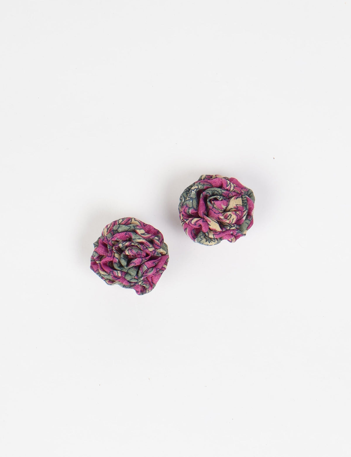 Pair of pink abstract ruffle fabric earrings with green and beige floral pattern, flat lay on white background