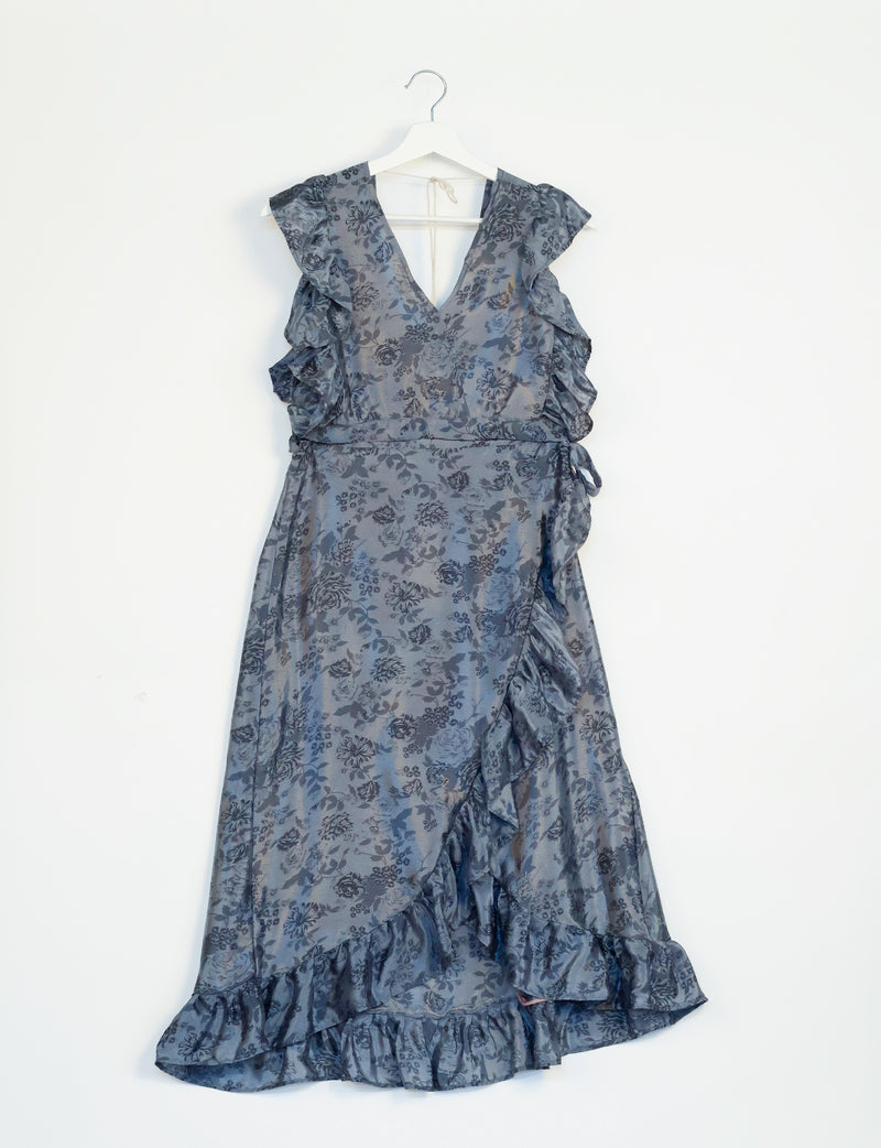 Grey tropical floral print frill skirt dress with V-neck and ruffle details, hanging on white hanger against white background