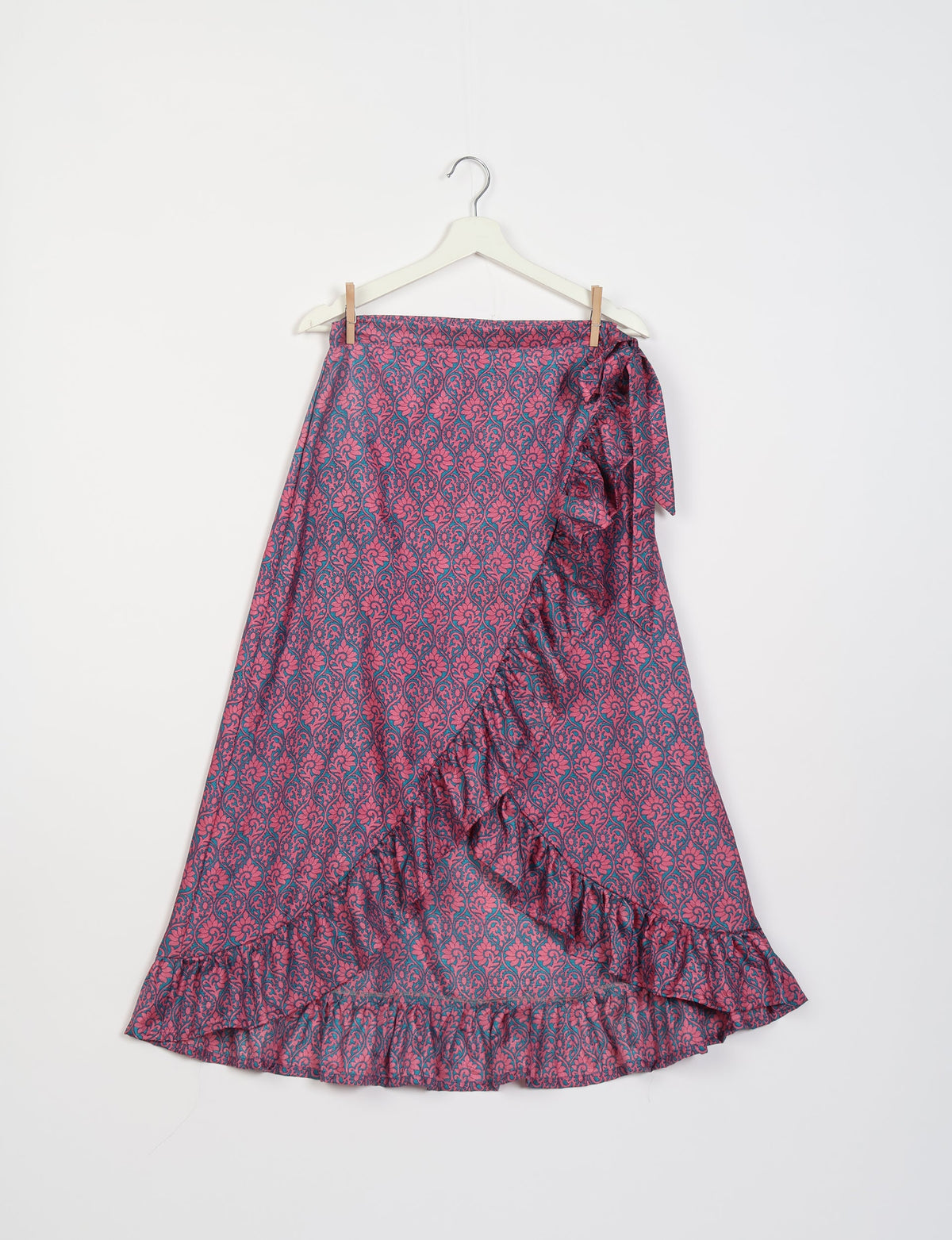Pink and blue floral patterned frill skirt with ruffle trim hanging on white hanger against white background