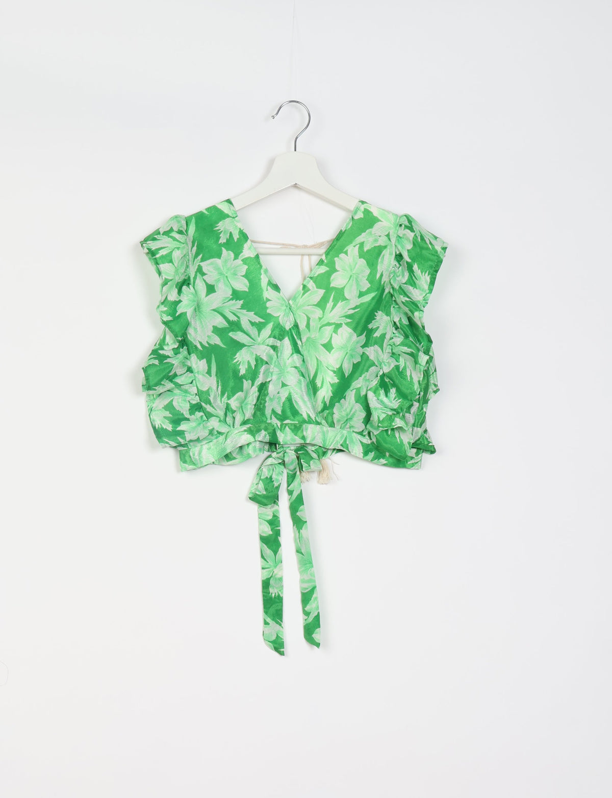 Green cropped wrap top with light green leaf print, ruffled sleeves, and tie belt, hanging on white hanger front view