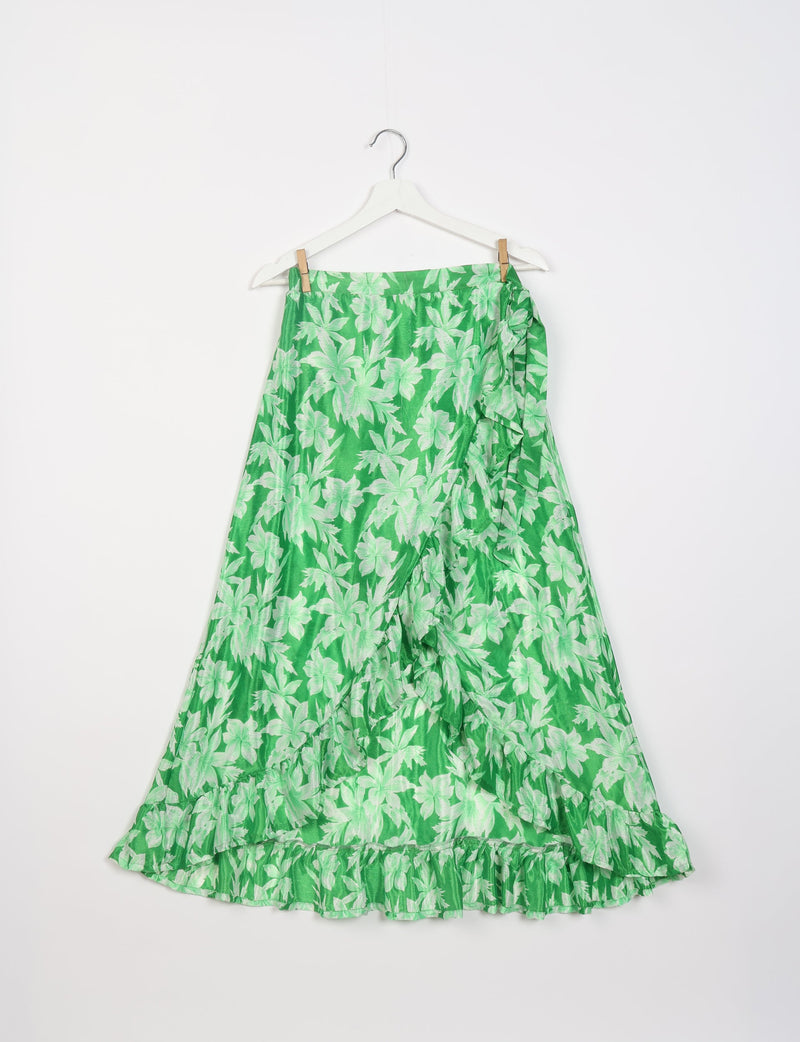 Green skirt with light green leaf print, frill hem, and side ruffle detail hanging on white hanger against white background