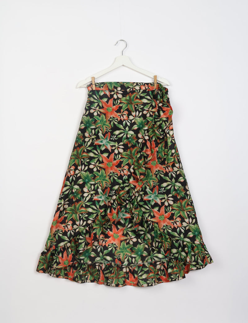 Black floral frill skirt with green and orange flowers, ruffled hem, hanging on white hanger against white background