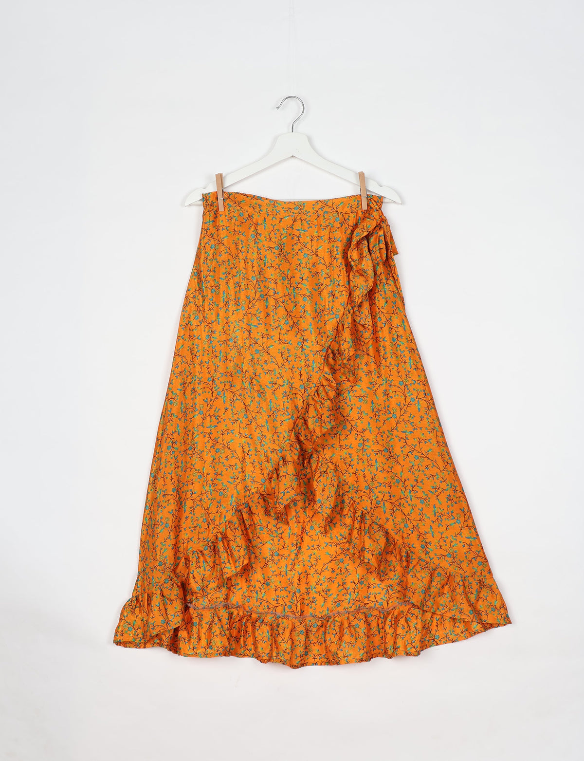 Yellow tropical floral print skirt with frill detail along front and hem, hanging on white hanger against white background
