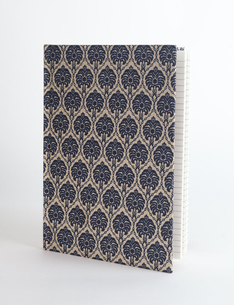 A5 hard cover notebook with beige fabric cover featuring a repeating dark blue leaf pattern, shown standing open with lined pages