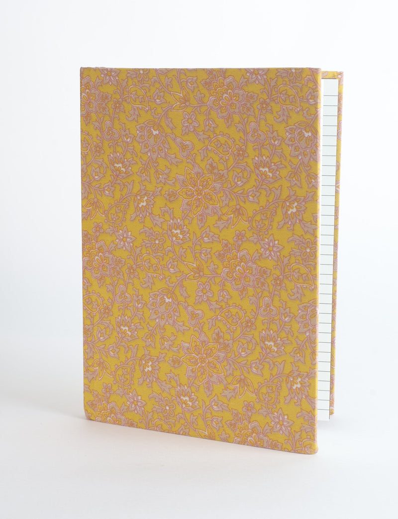 A5 hard cover notebook with yellow floral fabric cover, shown standing partially open with lined pages visible