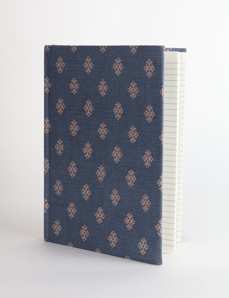 A5 hard cover notebook with blue fabric cover featuring a small brown geometric pattern, shown partially open with lined pages