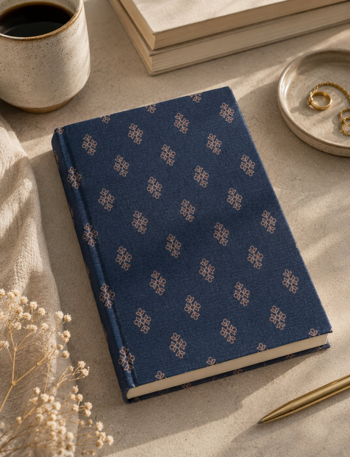 A5 hard cover notebook with blue fabric cover featuring a small repeating beige geometric pattern, flat on table