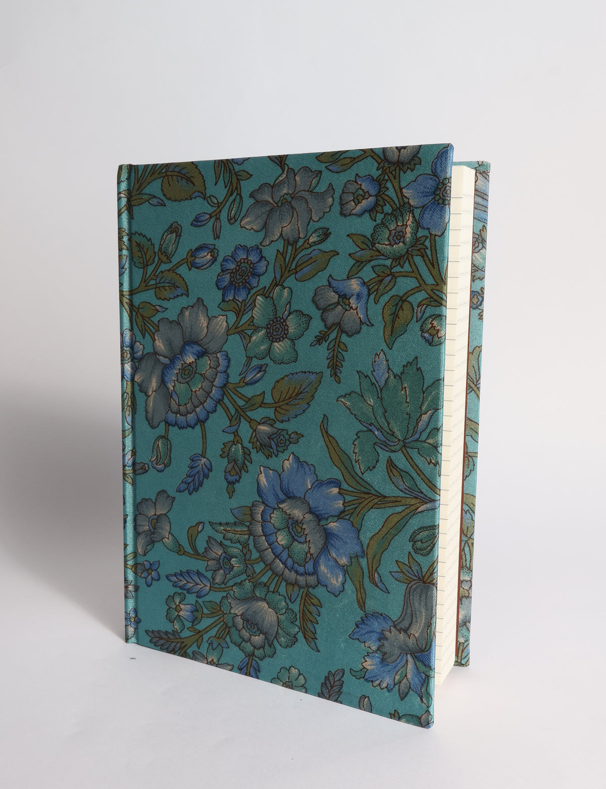 A5 hard cover notebook with dark blue cover featuring beige floral pattern, shown partially open with lined pages visible