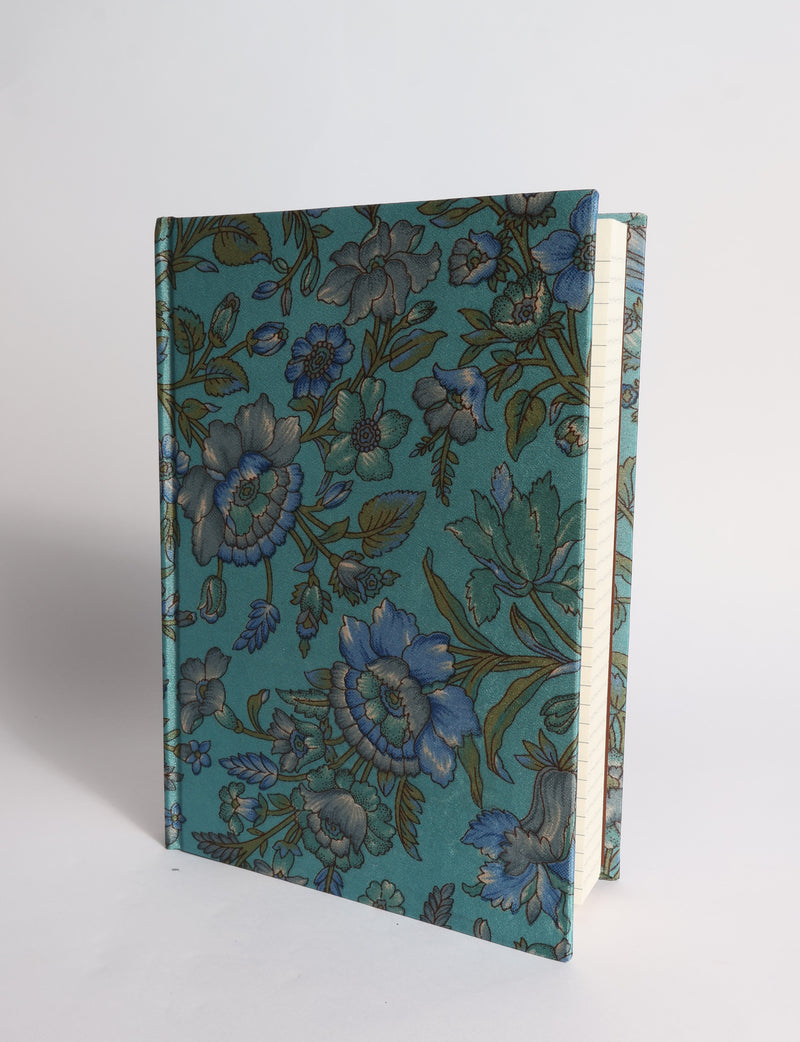 A5 hard cover notebook with dark blue cover featuring beige floral pattern, shown partially open with lined pages visible