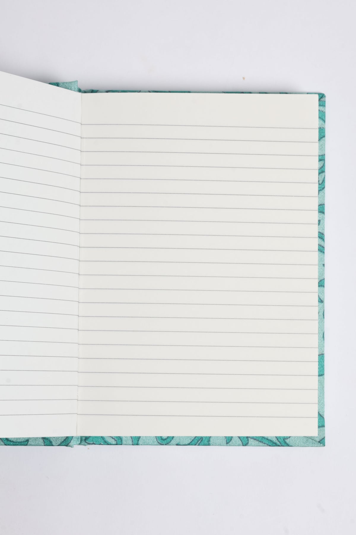Open A6 hard cover notebook with lined pages and a turquoise pre-loved sari fabric cover visible at edges