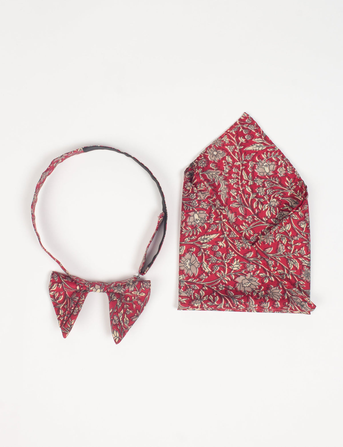 Red tropical floral patterned bow tie and matching pocket square set displayed flat on white background