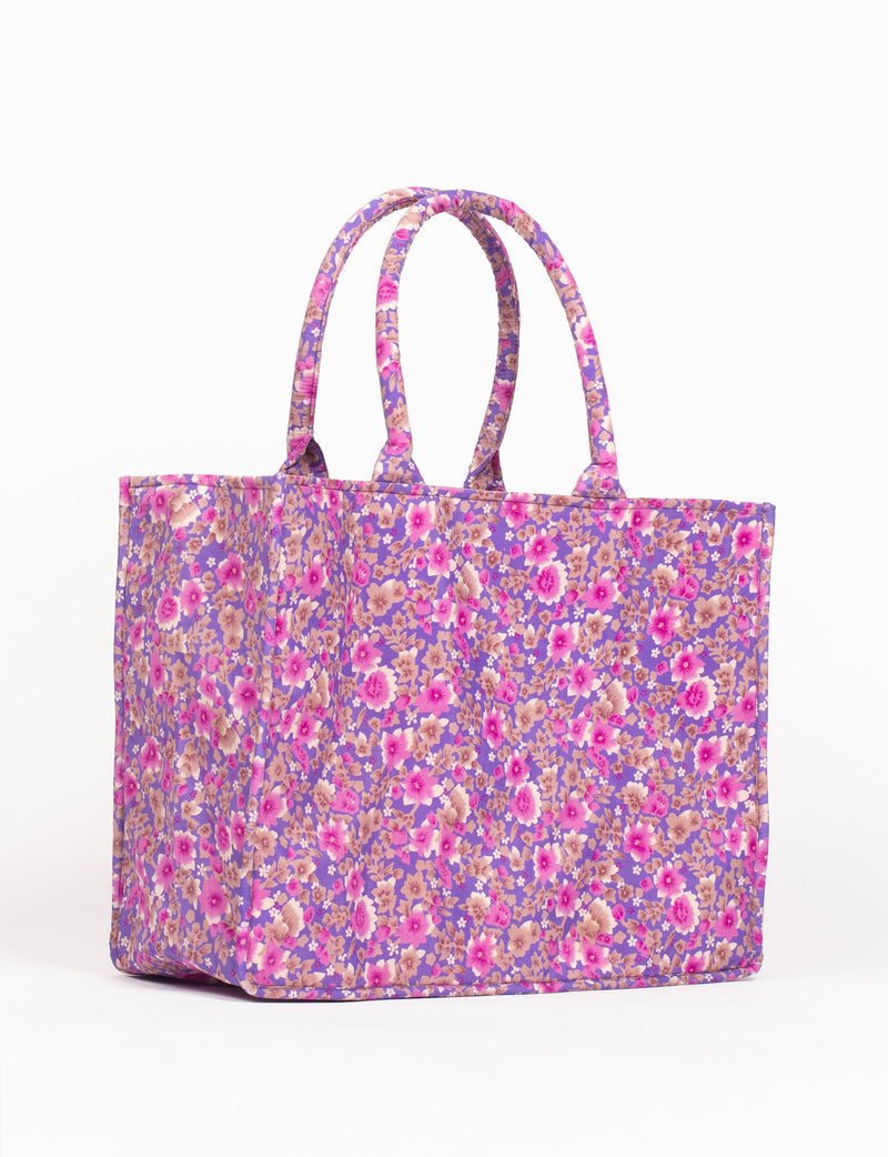 Purple floral fabric work tote bag with two padded handles, shown from side angle on white background