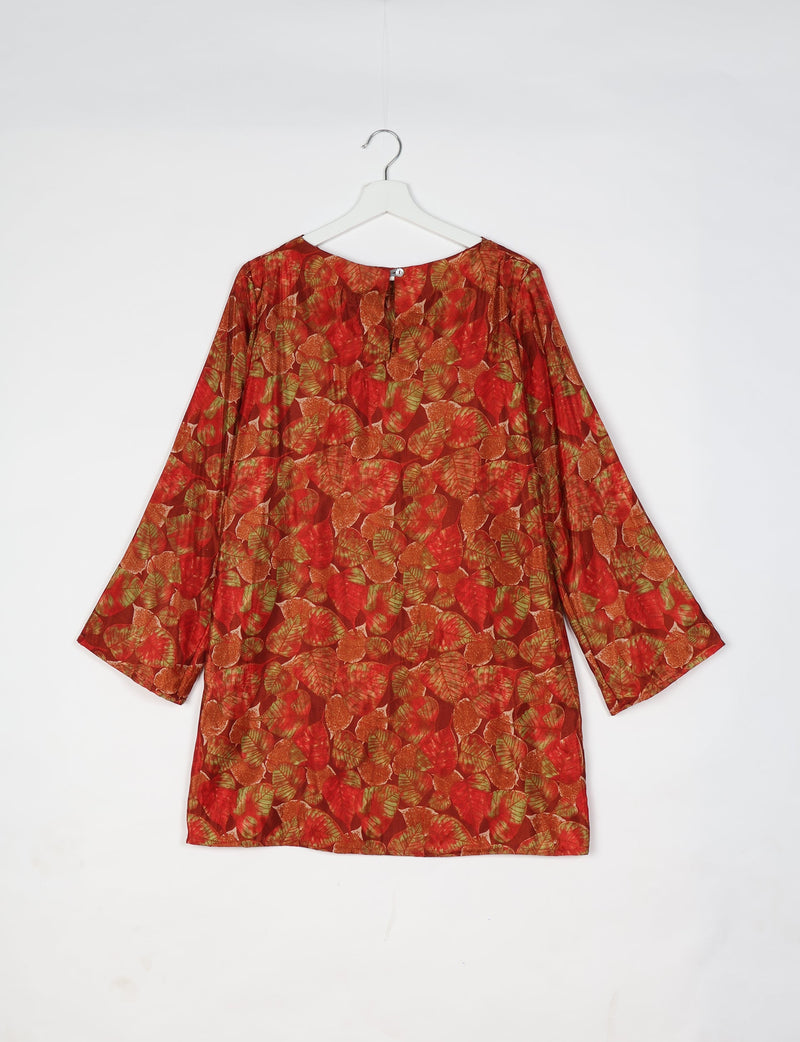 Red swing dress with all-over leaf pattern in shades of red, orange, and green, shown hanging from a white hanger