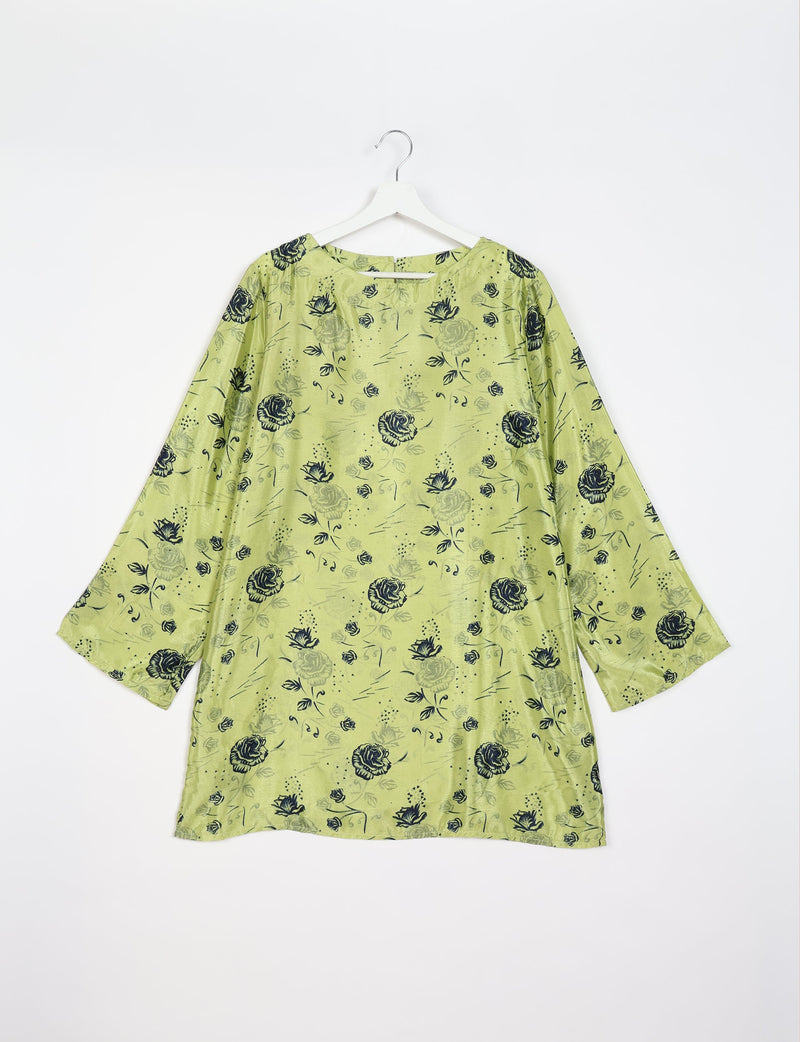 Green swing dress with black floral print, round neckline, and long sleeves hanging on white hanger against white background