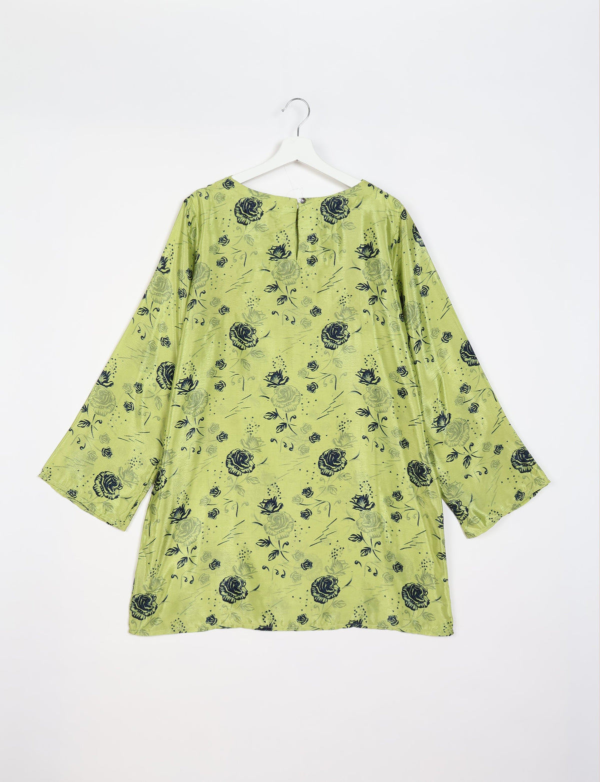 Green swing dress with black floral print, long sleeves, and a back button closure, shown hanging on a white hanger