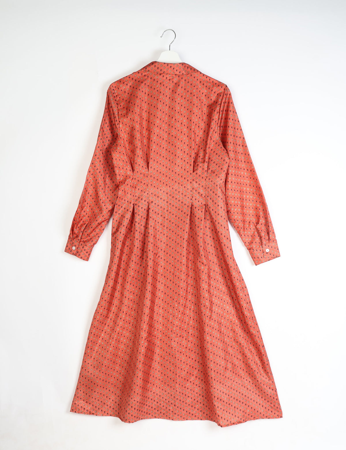 Orange midi shirt dress with micro floral pattern, long sleeves, buttoned cuffs, and pleated back, shown hanging flat
