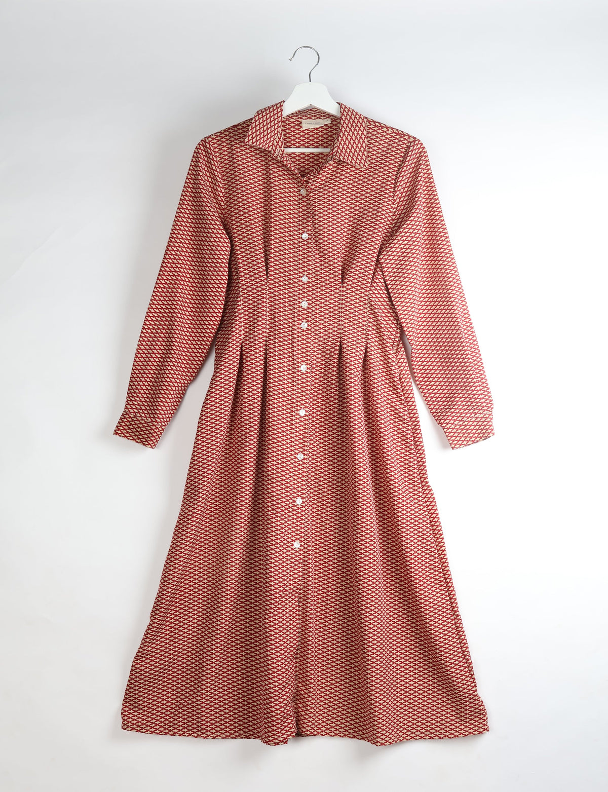 Orange midi shirt dress with micro geometric pattern, long sleeves, collar, and front button closure, hanging on white hanger