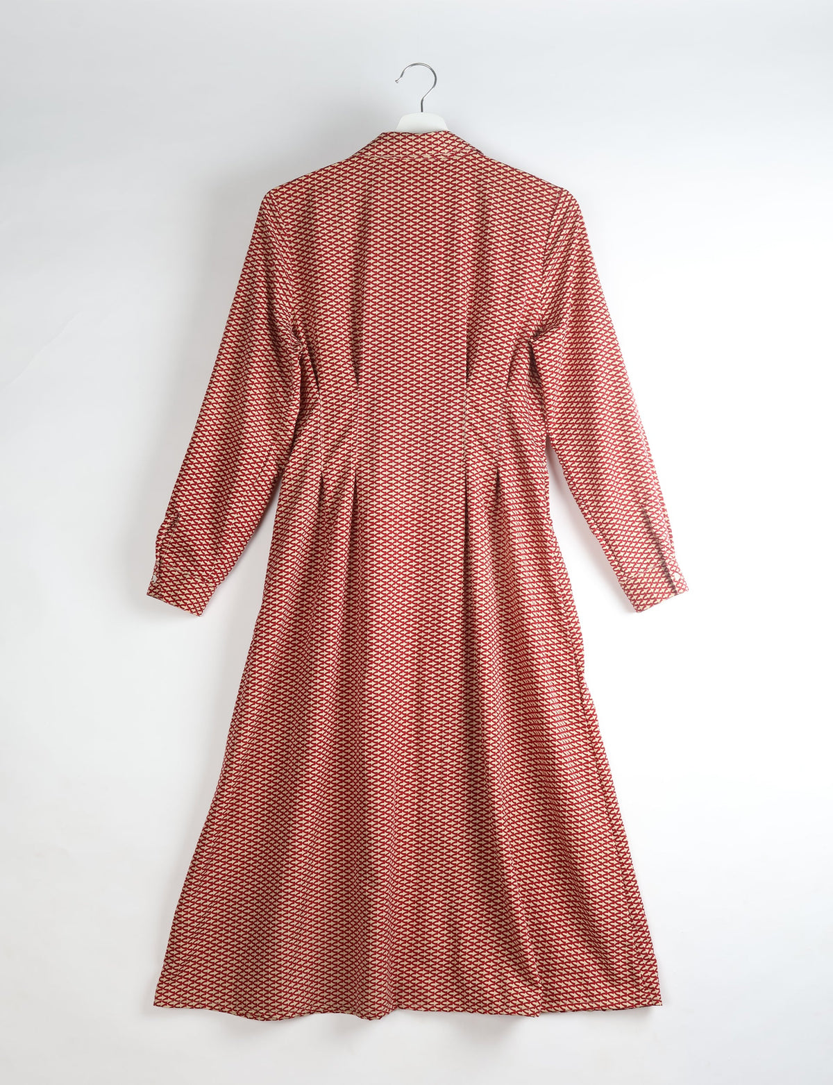 Orange midi shirt dress with micro geometric pattern, long sleeves, collar, and pleated back, hanging on white hanger