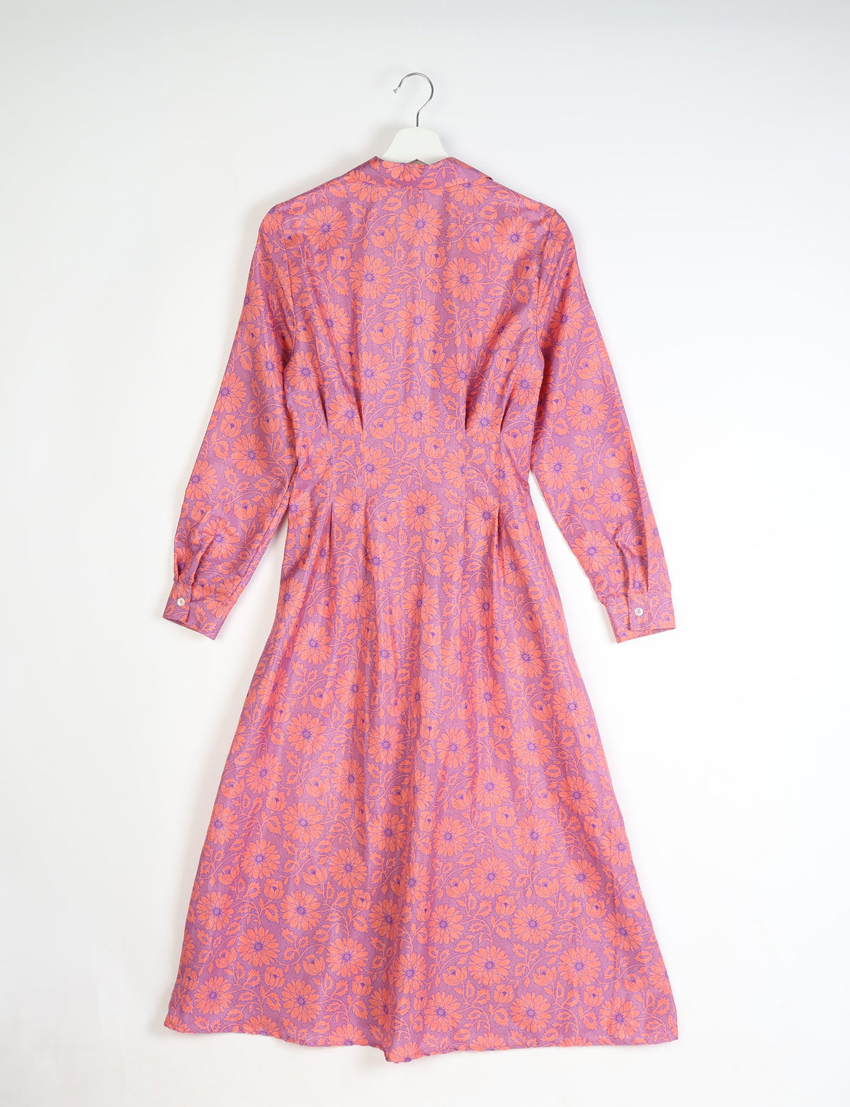 Long-sleeve midi dress with pink floral pattern on purple fabric, shown from back on white hanger against white background