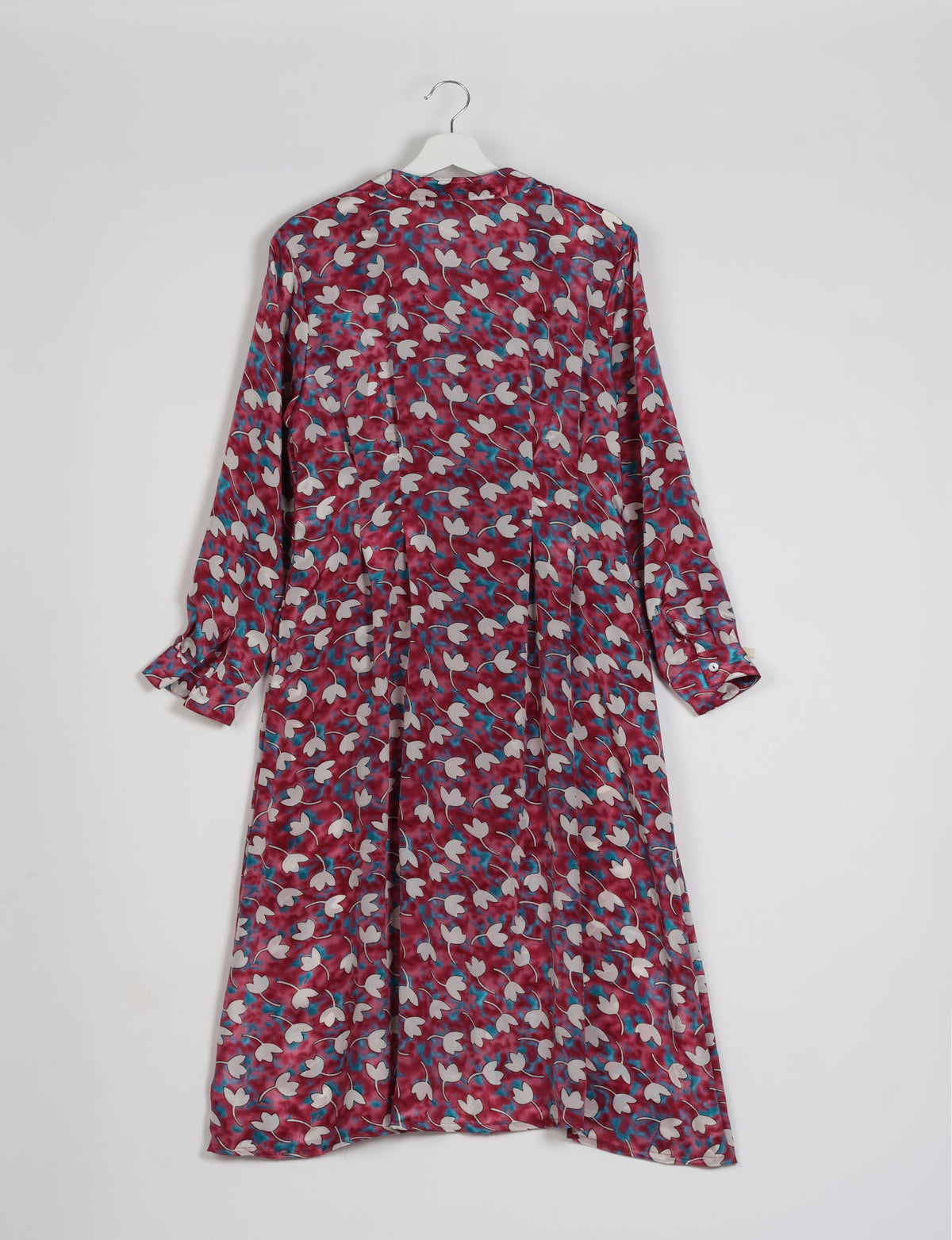 Pink floral midi shirt dress with long sleeves and buttoned cuffs hanging on white hanger, back view
