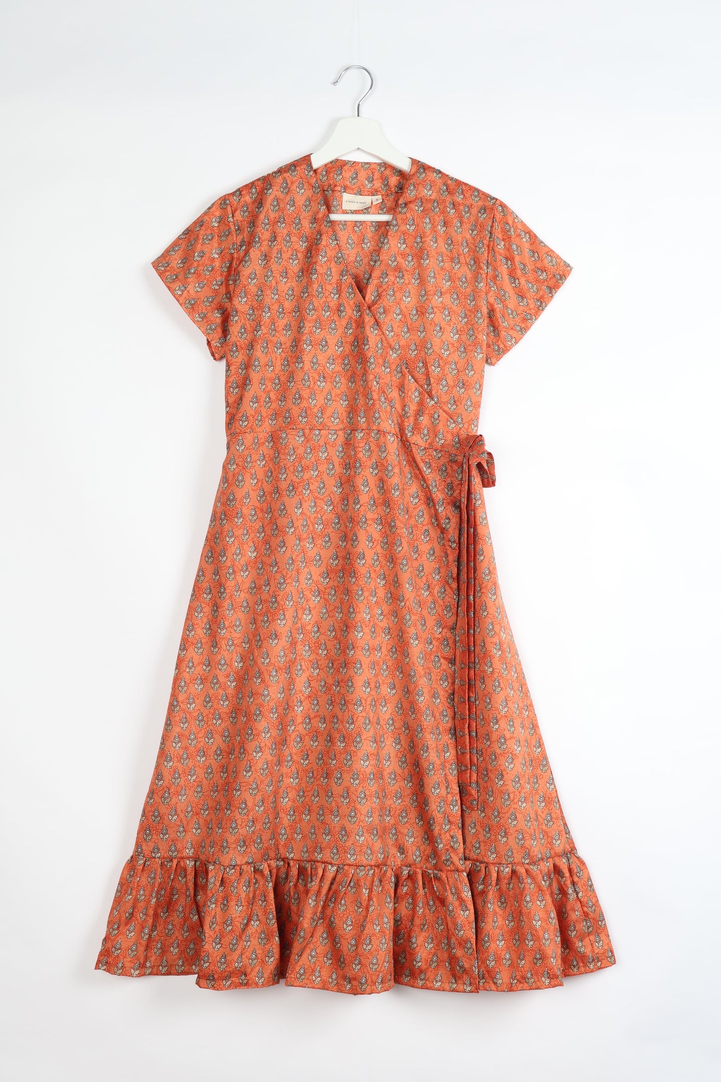 Embrace timeless elegance with our MIDI WRAP DRESS – a midi-length beauty featuring a v-neck, flattery from all angles, and a charming sari belt. Crafted from sustainable materials, this dress embodies ethical clothing and green fashion. Sophisticated with a frill tier at the hem and short cap sleeves, this dress is perfect for any occasion. Tie up the beautifully crafted sari belt on the side for a versatile, stylish, and eco-friendly look.