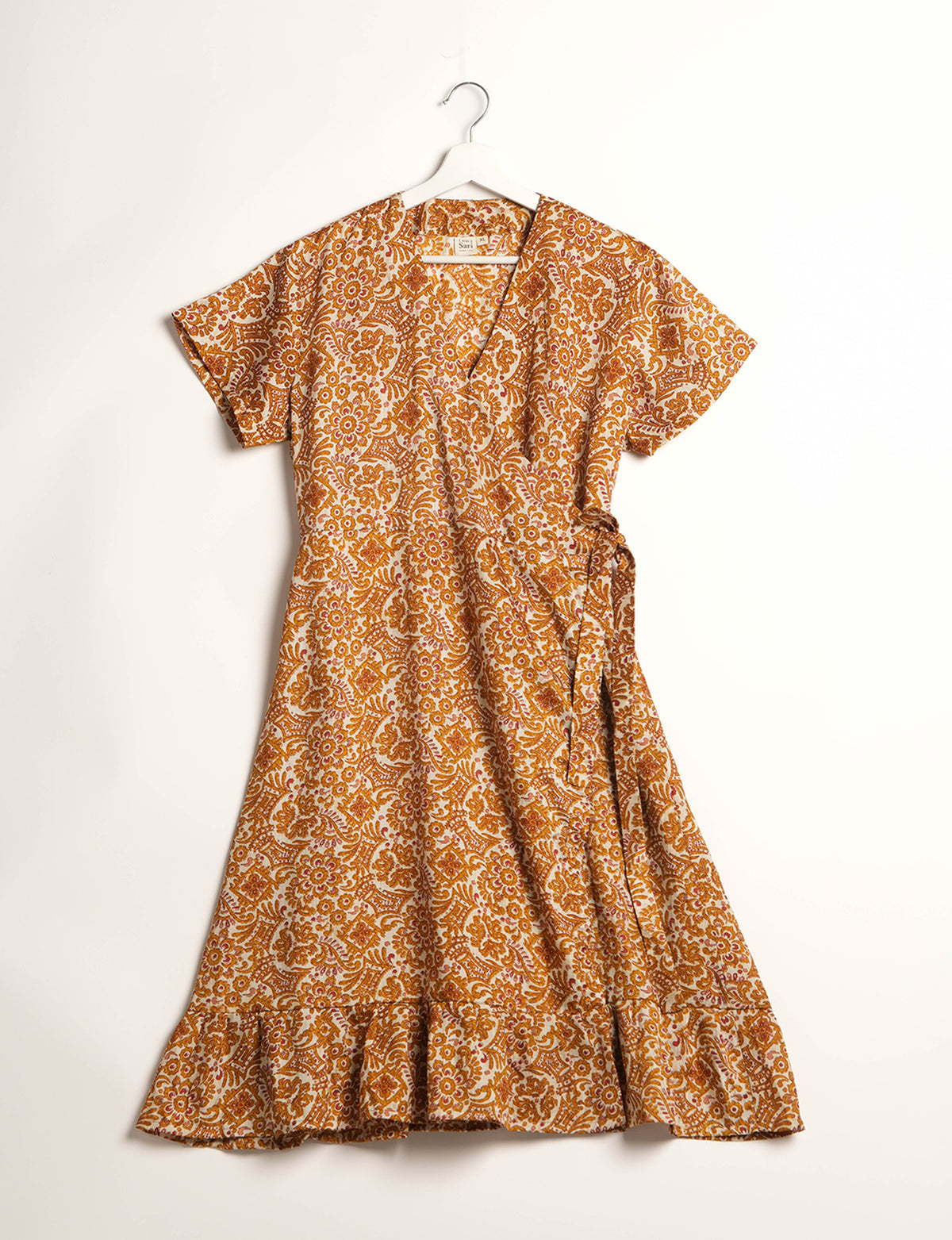 Embrace timeless elegance with our MIDI WRAP DRESS – a midi-length beauty featuring a v-neck, flattery from all angles, and a charming sari belt. Crafted from sustainable materials, this dress embodies ethical clothing and green fashion. Sophisticated with a frill tier at the hem and short cap sleeves, this dress is perfect for any occasion. Tie up the beautifully crafted sari belt on the side for a versatile, stylish, and eco-friendly look.