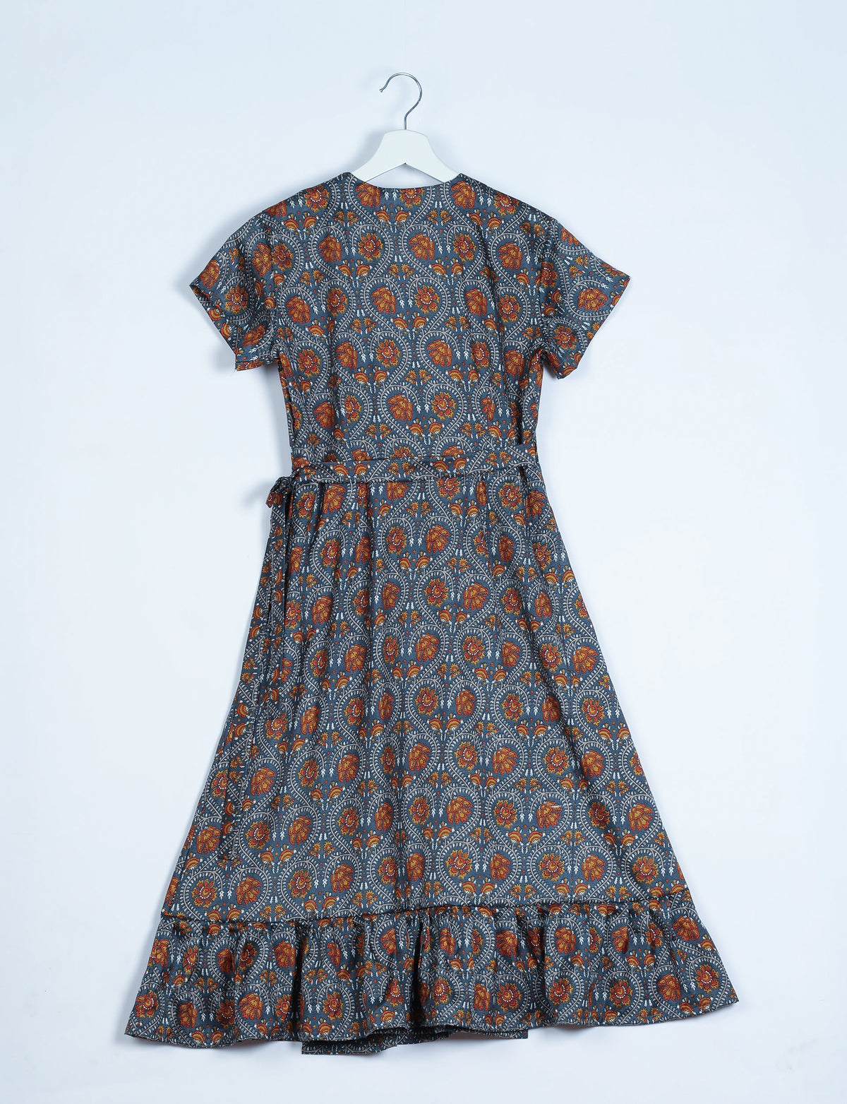 Grey midi wrap dress with orange floral tropical print, short sleeves, ruffle hem, and waist tie, shown from back on hanger