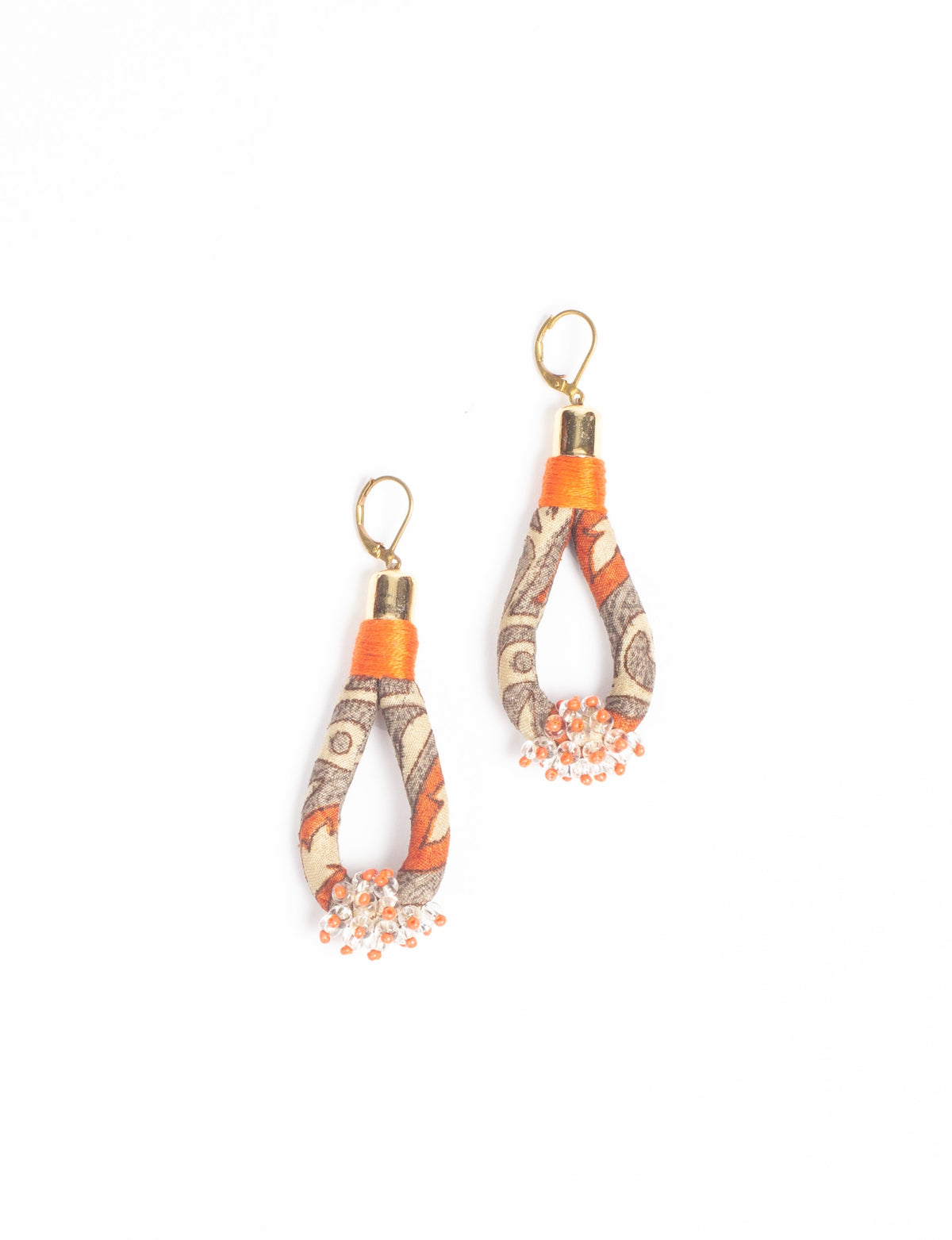 Orange tropical beaded drop earrings with gold hooks and fabric loops featuring a brown and beige pattern, flat lay view