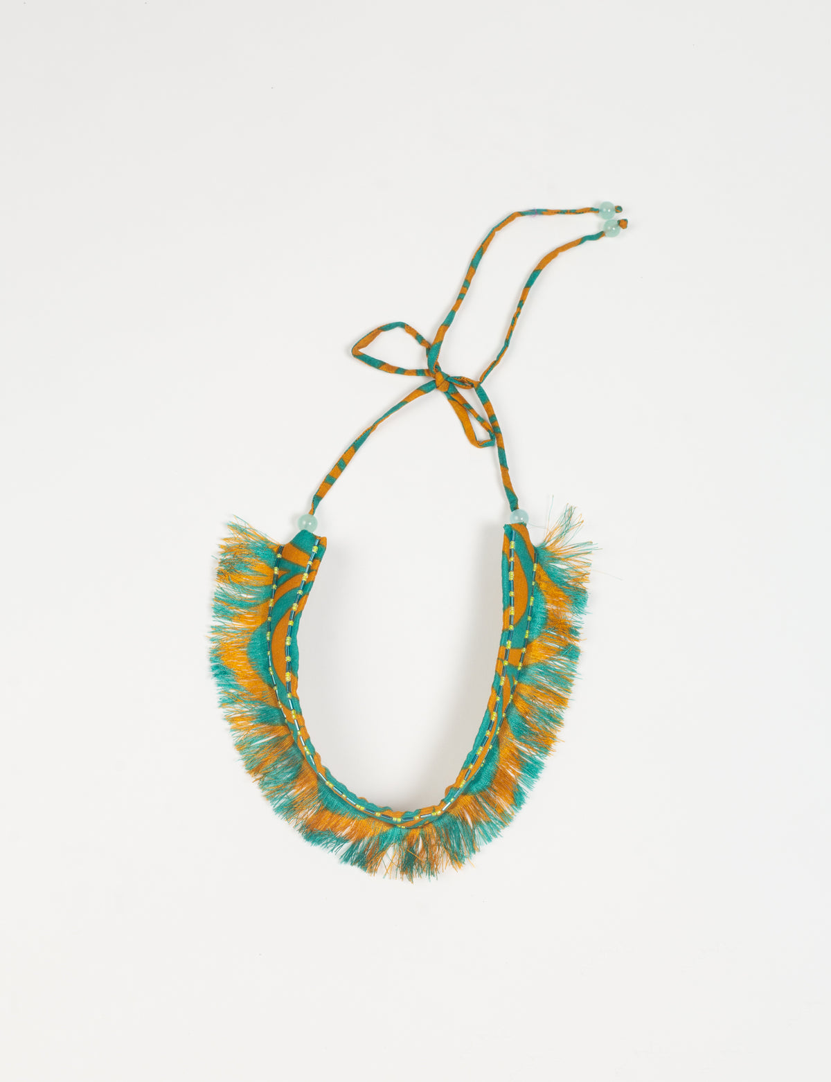 Yellow and teal abstract patterned fabric tie-up choker with fringe edges and bead details, flat lay on white background